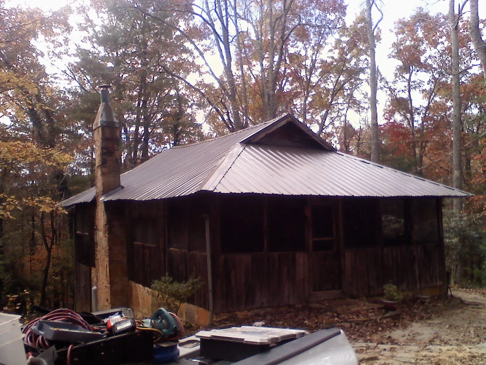 Brown metal hip roof on an old cabin with a stone chimney in Asheboro