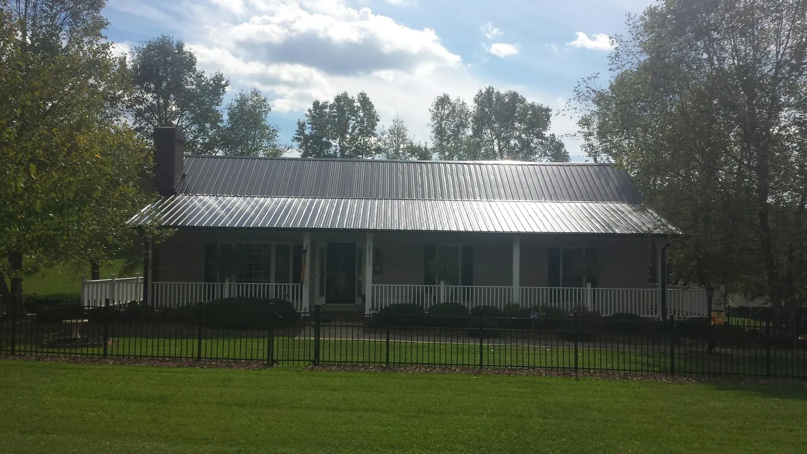 Gray metal roof on a brick ranch with a full width front porch — Gutter Guard Installation work by our crew in Asheboro