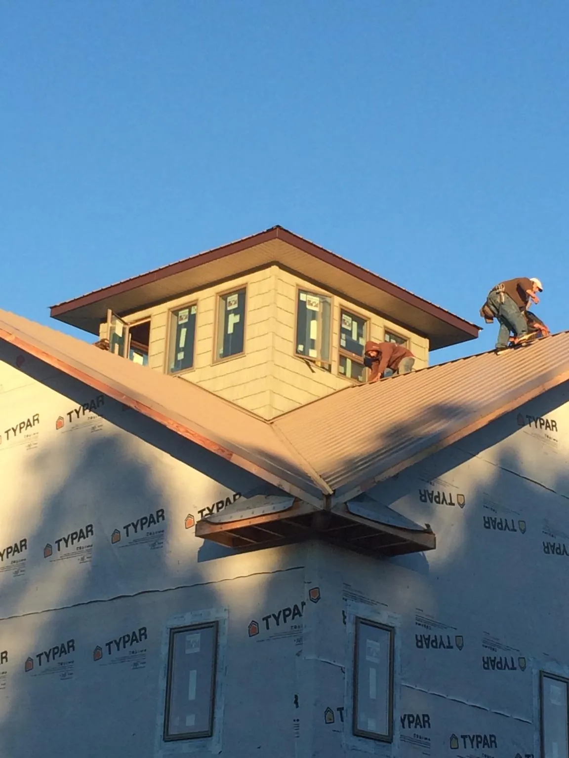 Roofers working around a rooftop cupola on a new metal roof at sunset — Roof Waterproofing in Asheboro by Roofing Brothers